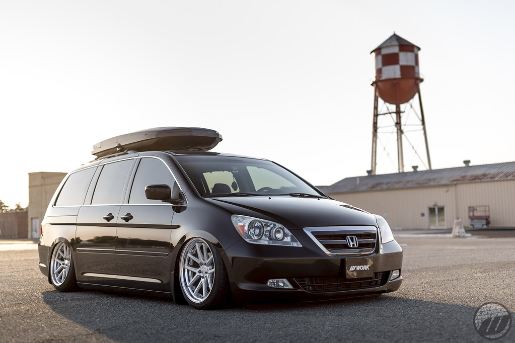 Black Honda Odyssey lowered on polished wheels with a roof box, photographed at golden hour